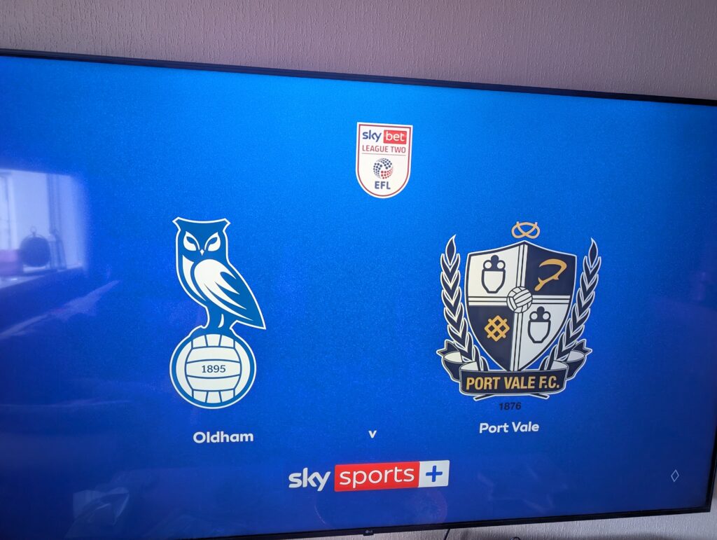 A television screen showing the Sky Sports pre-match graphic for Oldham v Port Vale, with both club badges either side of the Sky Bet League Two logo.