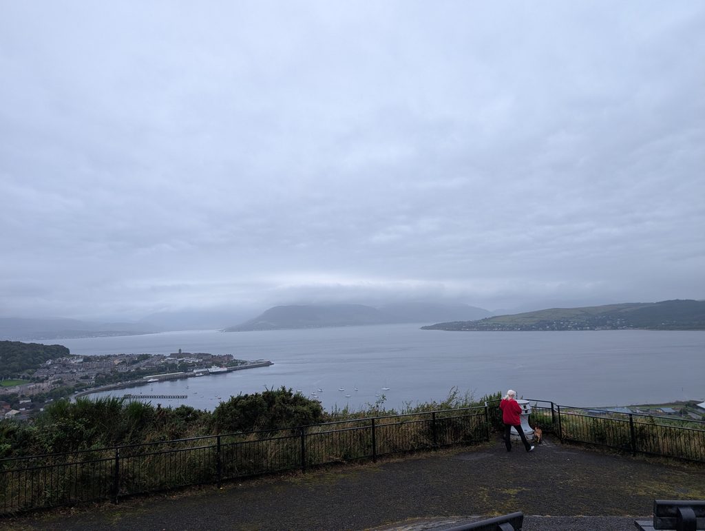 Stephanie and Chipshop the dog standing at a railing overlooking the misty Firth of Clyde