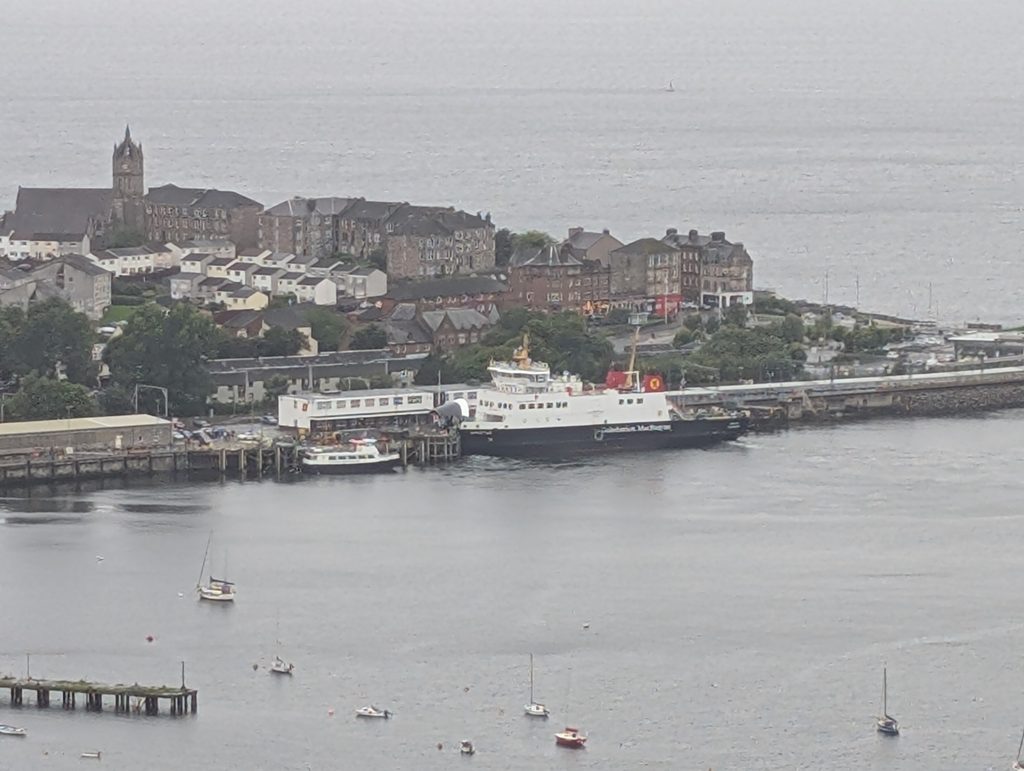 A CalMac ferry docked at Dunoon pier, with small boats moored in the foreground